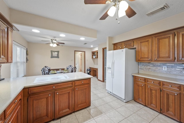 kitchen with brown cabinetry, white appliances, visible vents, and a peninsula