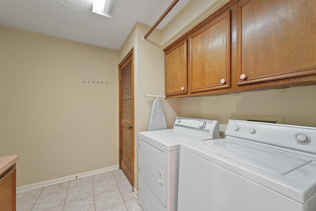 washroom featuring light tile patterned flooring, cabinet space, baseboards, and separate washer and dryer