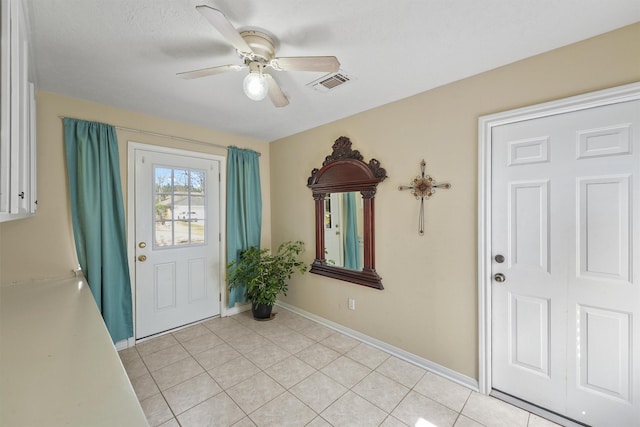 foyer featuring baseboards, visible vents, ceiling fan, and light tile patterned flooring