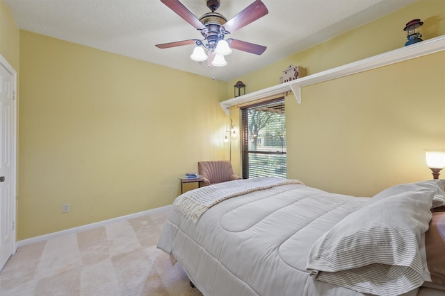 bedroom with a ceiling fan, light carpet, and baseboards