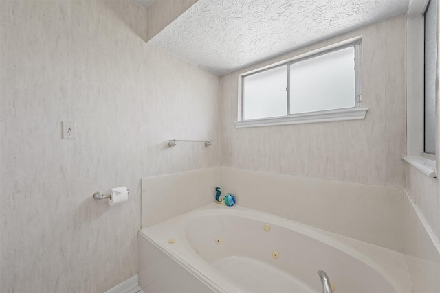 bathroom with a tub with jets and a textured ceiling