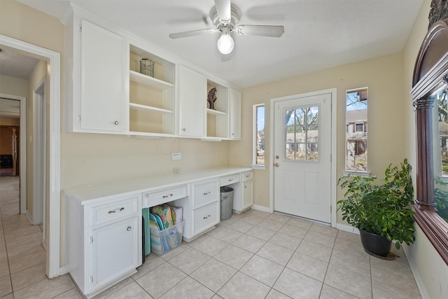 interior space featuring white cabinets, open shelves, built in desk, and light countertops