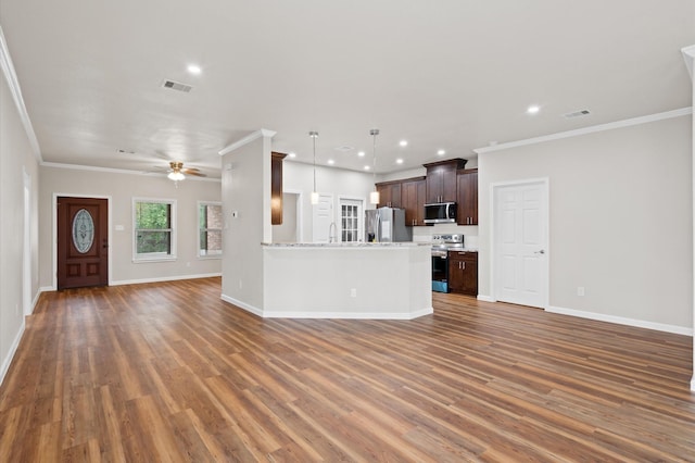 unfurnished living room with baseboards, visible vents, wood finished floors, and ornamental molding