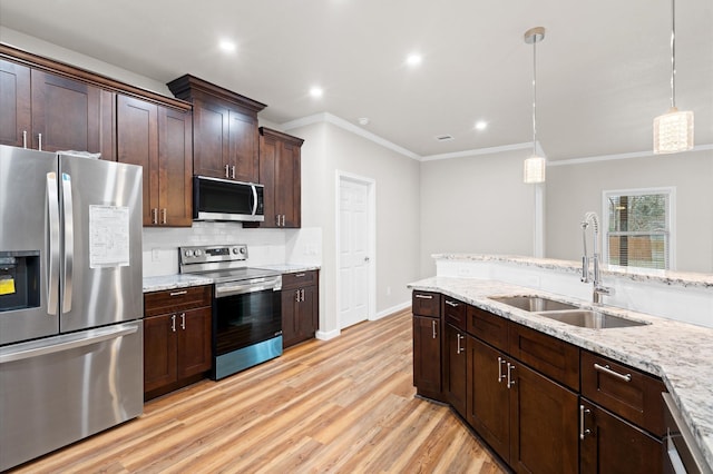 kitchen featuring pendant lighting, stainless steel appliances, backsplash, light wood-style floors, and a sink