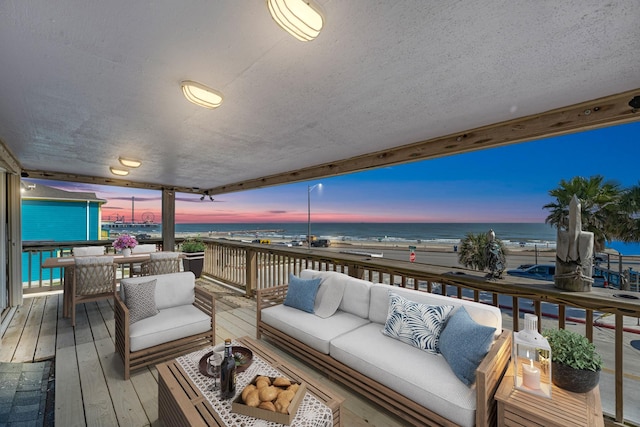 deck at dusk with an outdoor hangout area and a water view