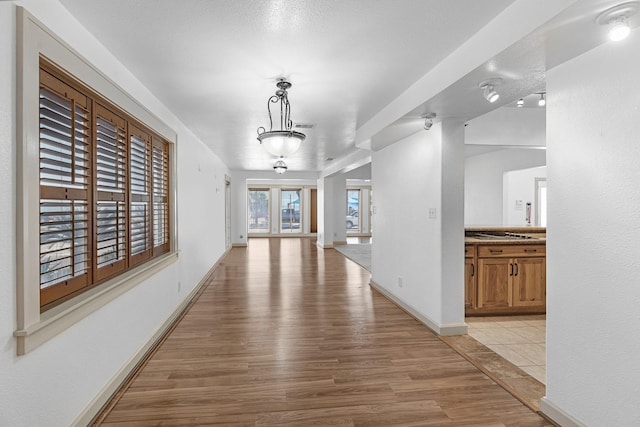 hall featuring light wood-style flooring, visible vents, and baseboards