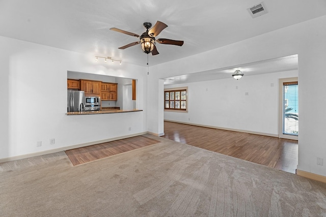 unfurnished living room with a healthy amount of sunlight, carpet, visible vents, and ceiling fan