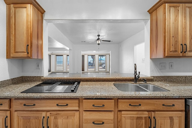 kitchen with light stone counters, a sink, ceiling fan, a peninsula, and black electric cooktop