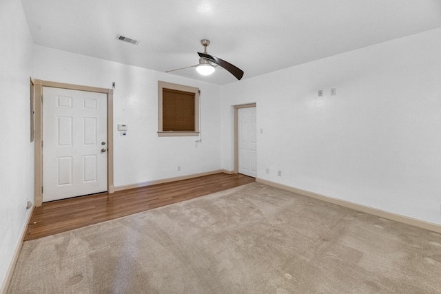 unfurnished room featuring baseboards, visible vents, a ceiling fan, wood finished floors, and carpet flooring