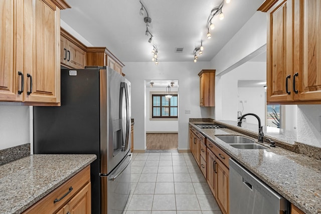 kitchen featuring appliances with stainless steel finishes, light tile patterned flooring, a sink, and light stone countertops