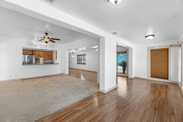 unfurnished living room featuring ceiling fan, light wood finished floors, visible vents, and baseboards