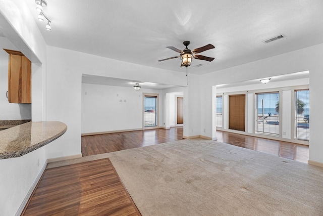 unfurnished living room with a healthy amount of sunlight, baseboards, visible vents, and wood finished floors