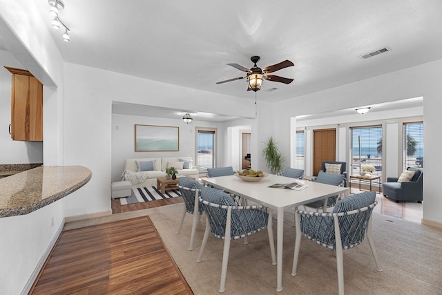 dining room with a ceiling fan, light wood-type flooring, visible vents, and baseboards