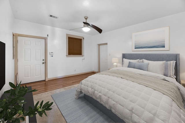 bedroom featuring a ceiling fan, visible vents, baseboards, and wood finished floors