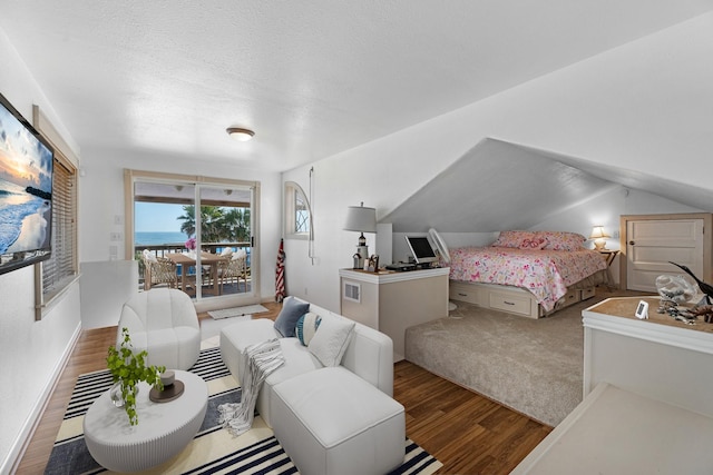 bedroom with access to exterior, a textured ceiling, vaulted ceiling, and wood finished floors