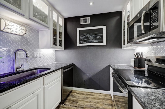 kitchen featuring stainless steel appliances, dark wood-type flooring, a sink, visible vents, and white cabinetry