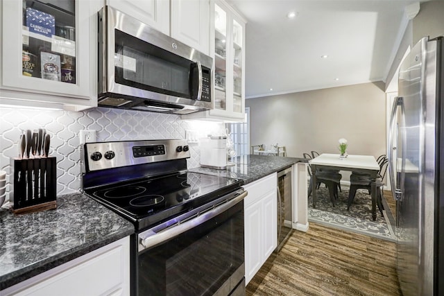 kitchen with stainless steel appliances, white cabinets, ornamental molding, and backsplash