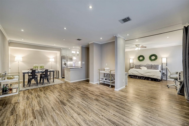 bedroom featuring stainless steel fridge, crown molding, visible vents, and wood finished floors