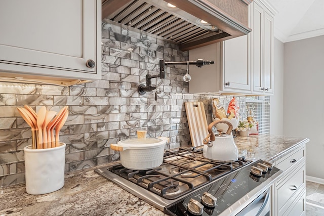 kitchen with ornamental molding, custom range hood, backsplash, white cabinetry, and gas stove