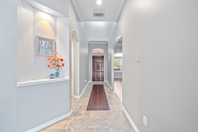 doorway with baseboards, arched walkways, and visible vents