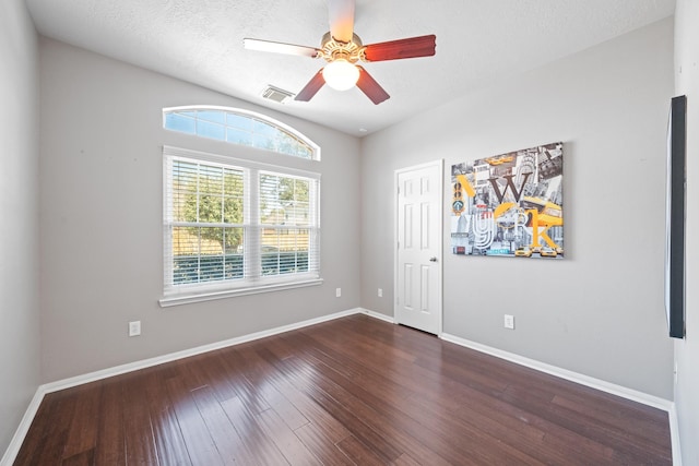 empty room with a ceiling fan, visible vents, wood finished floors, baseboards, and a textured ceiling