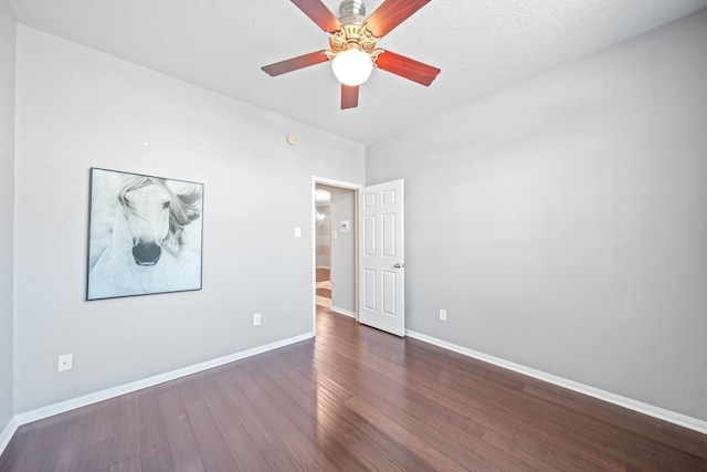 empty room featuring a ceiling fan, dark wood-type flooring, and baseboards