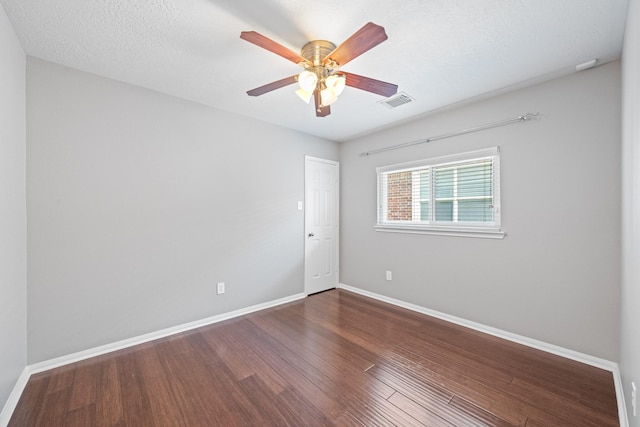 empty room featuring a ceiling fan, wood finished floors, visible vents, baseboards, and a textured ceiling