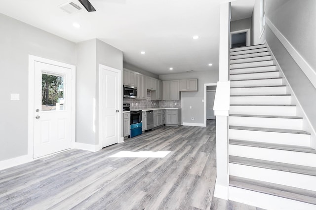 unfurnished living room with light wood finished floors, stairway, visible vents, and recessed lighting