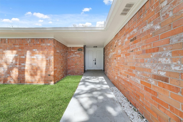 property entrance featuring visible vents and brick siding