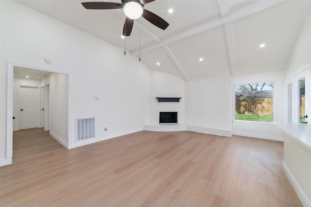 unfurnished living room featuring attic access, visible vents, light wood-style flooring, a fireplace, and high vaulted ceiling