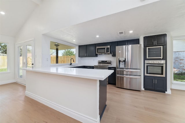 kitchen featuring a peninsula, light wood-style floors, appliances with stainless steel finishes, and light countertops