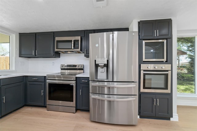 kitchen with light wood-style flooring, visible vents, stainless steel appliances, and light countertops