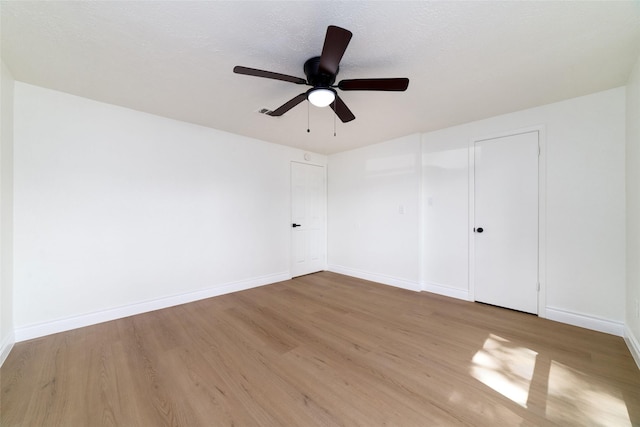 spare room featuring a ceiling fan, baseboards, and wood finished floors