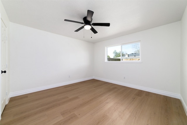 spare room featuring a ceiling fan, baseboards, and light wood finished floors