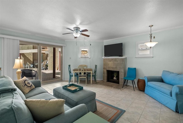 living area featuring light tile patterned floors, ceiling fan, a textured ceiling, a fireplace, and crown molding