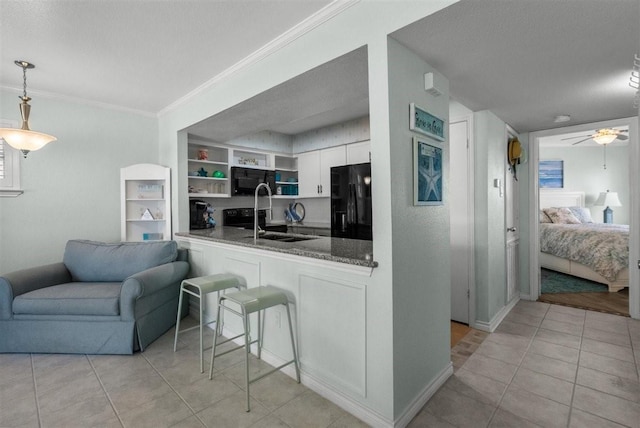 kitchen featuring light tile patterned floors, white cabinets, ornamental molding, black appliances, and a sink