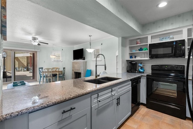 kitchen featuring light stone countertops, black appliances, a fireplace, open shelves, and a sink