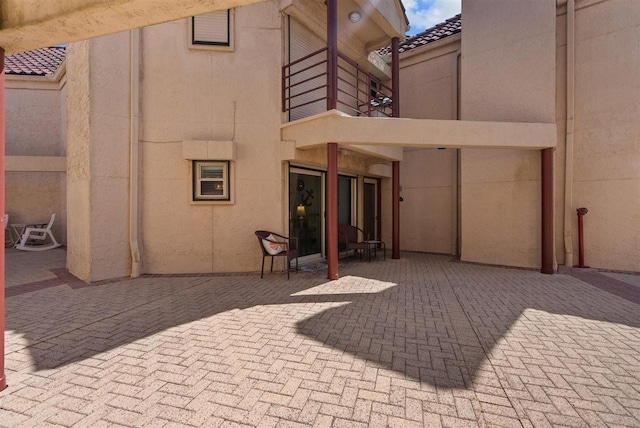 exterior space with a patio area, a tiled roof, and stucco siding