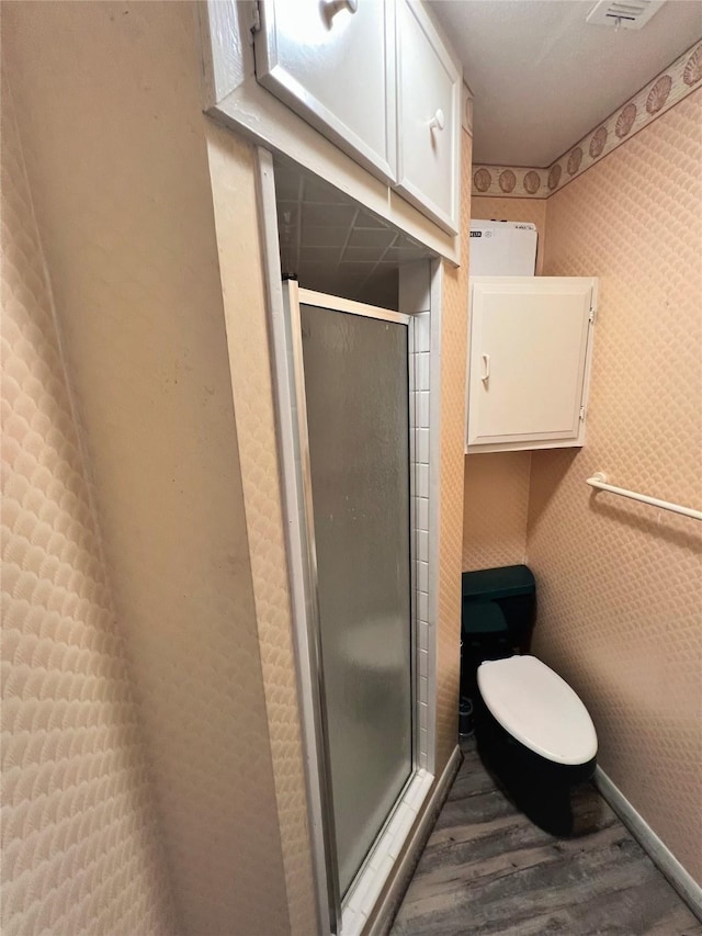 full bath featuring toilet, a stall shower, baseboards, and wood finished floors