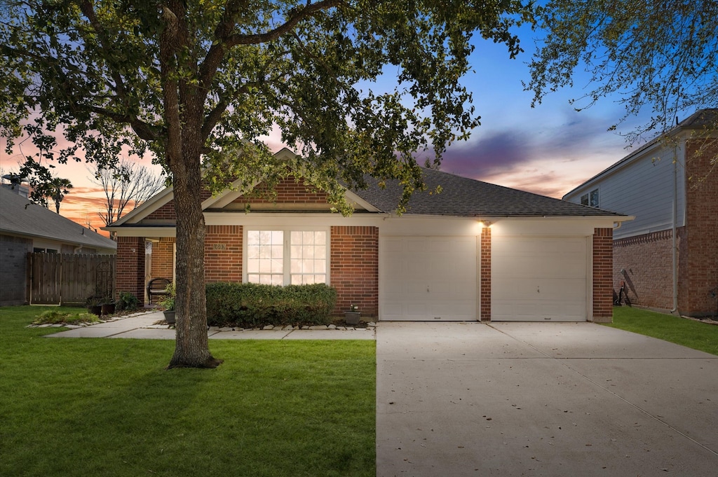 ranch-style home featuring brick siding, fence, concrete driveway, a yard, and a garage