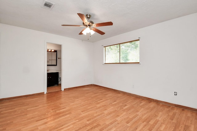 empty room featuring light wood finished floors, visible vents, and baseboards