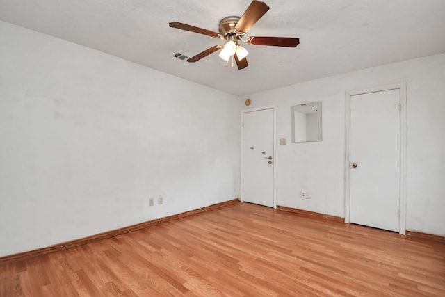 spare room featuring light wood-type flooring, baseboards, visible vents, and a ceiling fan