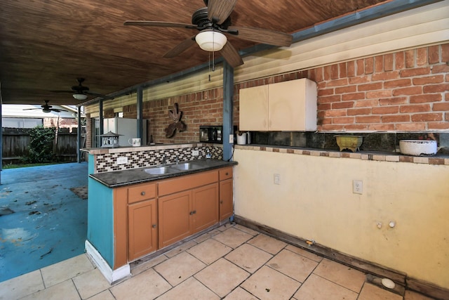 view of patio with an outdoor kitchen, a sink, a ceiling fan, and fence