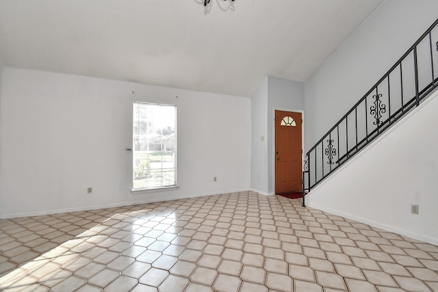 entryway featuring lofted ceiling, light floors, stairs, and baseboards