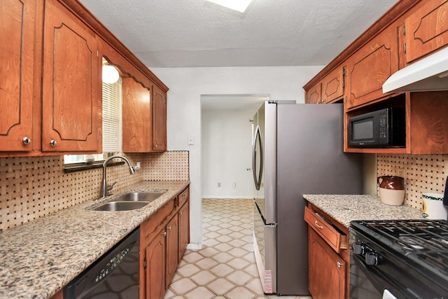 kitchen with black appliances, decorative backsplash, a sink, and brown cabinets