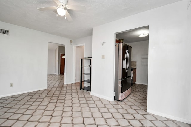 unfurnished room featuring light floors, ceiling fan, visible vents, and baseboards