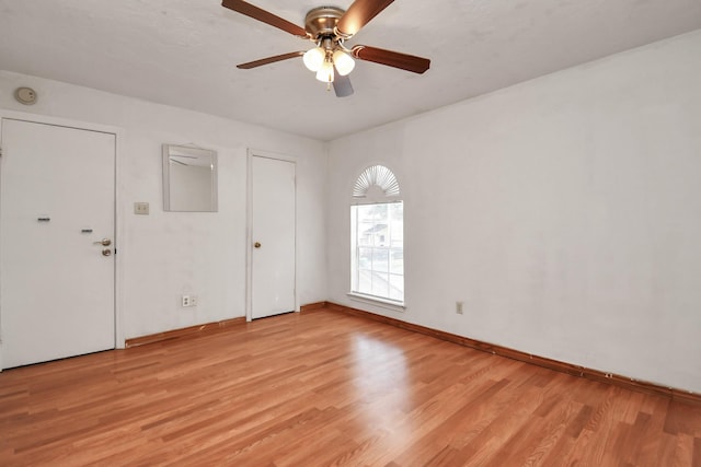 empty room featuring light wood-style flooring, baseboards, and a ceiling fan