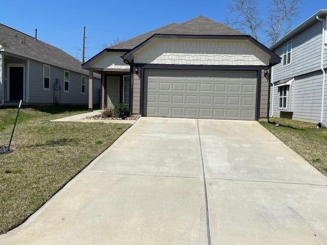 single story home featuring an attached garage, concrete driveway, and a front yard