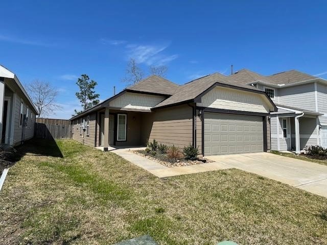 view of side of property with a garage, driveway, fence, and a lawn