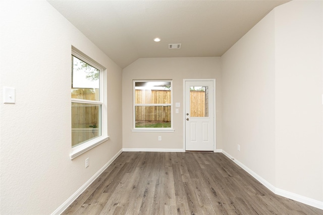 spare room with recessed lighting, visible vents, vaulted ceiling, wood finished floors, and baseboards